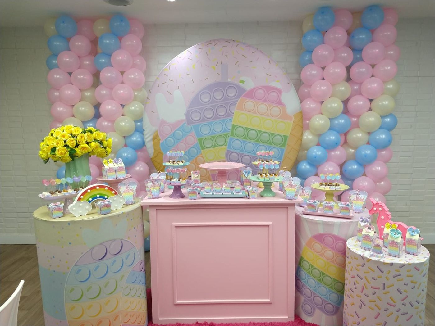 Mesa de festa em tons pastel com balões e doces